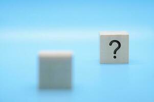 Question mark on wooden block with blue background. Question and answer session. photo