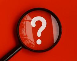 Question mark on red background with magnifying glass. Question and Answer session. photo