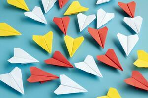 Yellow paper plane origami leading other white paper planes on blue background. Leadership concept. Origami concept. photo