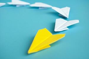 Low view of yellow paper plane origami leading white paper planes. With copy space for text. photo