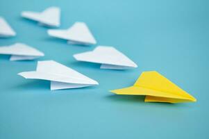 Yellow paper plane origami leading other white paper planes on blue background. Leadership concept photo