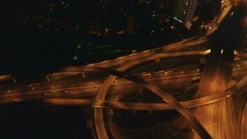 iluminado complejo intercambio y carros tráfico a noche. zumbido es volador alrededor. aéreo vertical disparo. video