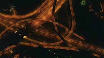 Illuminated multi-level road junction and cars traffic at night. Drone is spinning around at high altitude. Aerial vertical shot. video