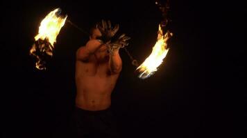 Muscular Man is performing trick by fireballs on chains rotation. Fire show. Slow motion. video