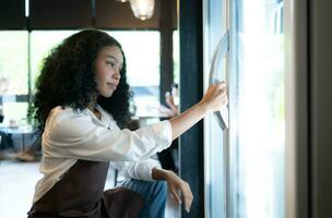 The owner of a coffee shop looks inside the refrigerator to retrieve chilled food to serve a customer. photo