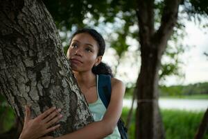 Portrait of a beautiful young woman with backpack standing and forest bathing photo