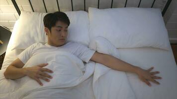 Young Asian man lying on the bed Use his hand to fumble his wife who thinks her woke up together that morning. photo