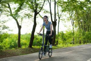 mujer montando un bicicleta en el parque. sano estilo de vida y deporte concepto. foto