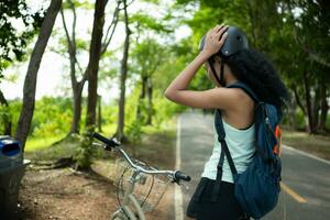 Rear view of a young woman collecting garbage in the park. It has a backpack with a solar panel for charging smartphone. photo