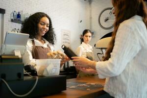 Young woman barista serves customers who bring their own cups in a coffee shop. photo