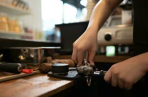 Cropped image of female barista using coffee machine in coffee shop photo