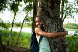 Portrait of a beautiful young woman with backpack standing and forest bathing photo