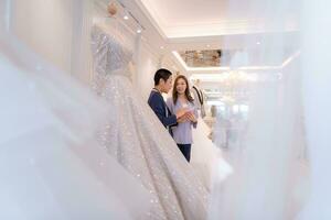 Both of asian fashion designers working with wedding dress in the wedding dress shop photo