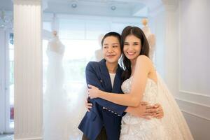 In the wedding dress shop, an LGBT couple asian embracing each other after the bride tries on the wedding dress photo