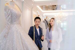 Both of asian fashion designers working with wedding dress in the wedding dress shop photo