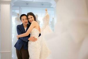 In the wedding dress shop, an LGBT couple asian embracing each other after the bride tries on the wedding dress photo