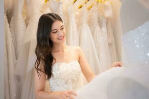 Portrait of beautiful asian woman wearing wedding dress in the wedding dress shop photo