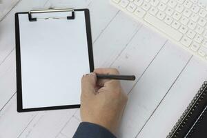 Hand with pencil writing something on the black clipboard. Copy space. photo