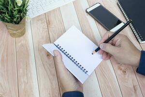 Businessman hands with pen writing notebook on office desk table. Copy space. photo