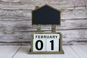 Chalkboard with February 01 date on white cube block on wooden table. photo