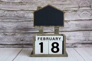 Chalkboard with date on white cube block on wooden table. photo