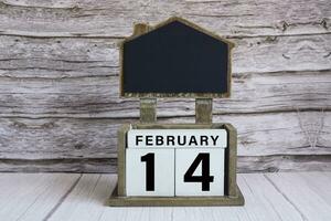 Chalkboard with date on white cube block on wooden table. photo