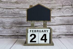 Chalkboard with date on white cube block on wooden table. photo