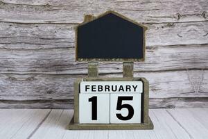 Chalkboard with date on white cube block on wooden table. photo