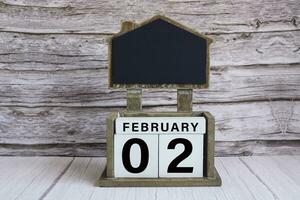 Chalkboard with date on white cube block on wooden table. photo