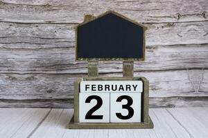 Chalkboard with date on white cube block on wooden table. photo