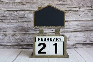 Chalkboard with date on white cube block on wooden table. photo