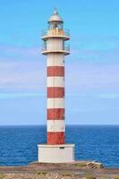 a red and white lighthouse on the coast photo