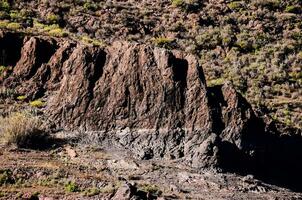 a mountain with a rocky face and a small hill photo