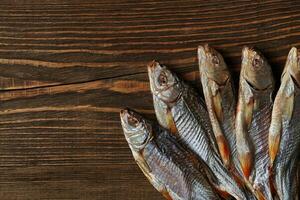 Dried or jerky salted roach, clipfish on wooden background. Salty beer appetizer. Traditional way of preserving fish. Close up photo