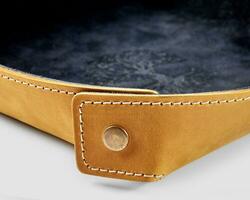 Closeup of sand-coloured leather tray with black suede lining photo