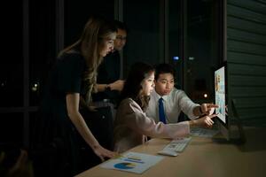 Group of business people working in office at night. Business concept. photo