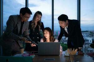 Group of broker international stock traders working actively at night in office, A young woman is working hustle to present a client with friends helping her with information. photo