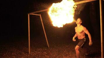 Muscular caucasian man is spraying kerosene on fire torch. Flame eruption and burning from mouth. Fire show. Slow motion. video