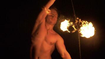 Muscular Man is performing fire show. Two fire balls are rotating on chain. video
