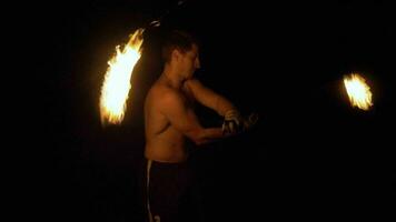 Muscular Man is spinning and rotating two fireballs on chains. Fire show. video