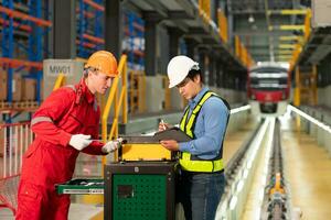 Electric train engineer and technician using repair tools of the electric train industry There is an electric train in the train repair factory as the background image. photo