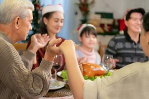 Young asian man praying with his family during Christmas dinner at home photo