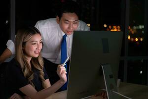 Both of young Asian broker international stock traders working together on desktop at night office, International financial investment company concept photo