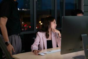 Group of business people working in office at night. Business concept. photo