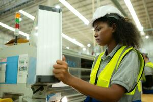 A young female warehouse worker is operating a machine by computer control panel side to the machine. photo