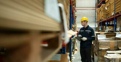 Young male warehouse worker checking stock in a warehouse. This is a large paper package storage and distribution warehouse. photo