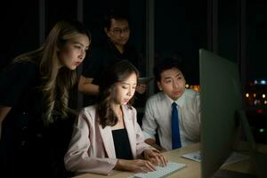 Group of business people working in office at night. Business concept. photo