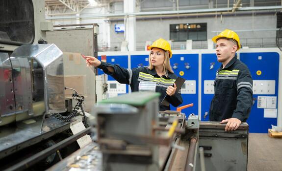 Both of engineer workers working on a machine in a factory. Industrial background photo