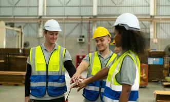 Front view of a diverse group of warehouse workers holding hands to encourage each other in their work. photo