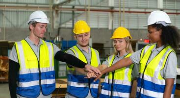 Front view of a diverse group of warehouse workers holding hands to encourage each other in their work. photo